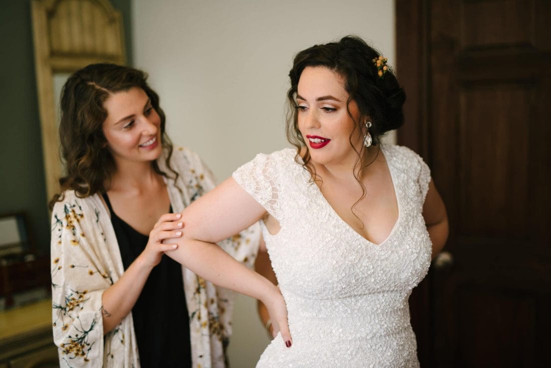 Jessica with her sister getting into wedding dress in Oakland apartment
