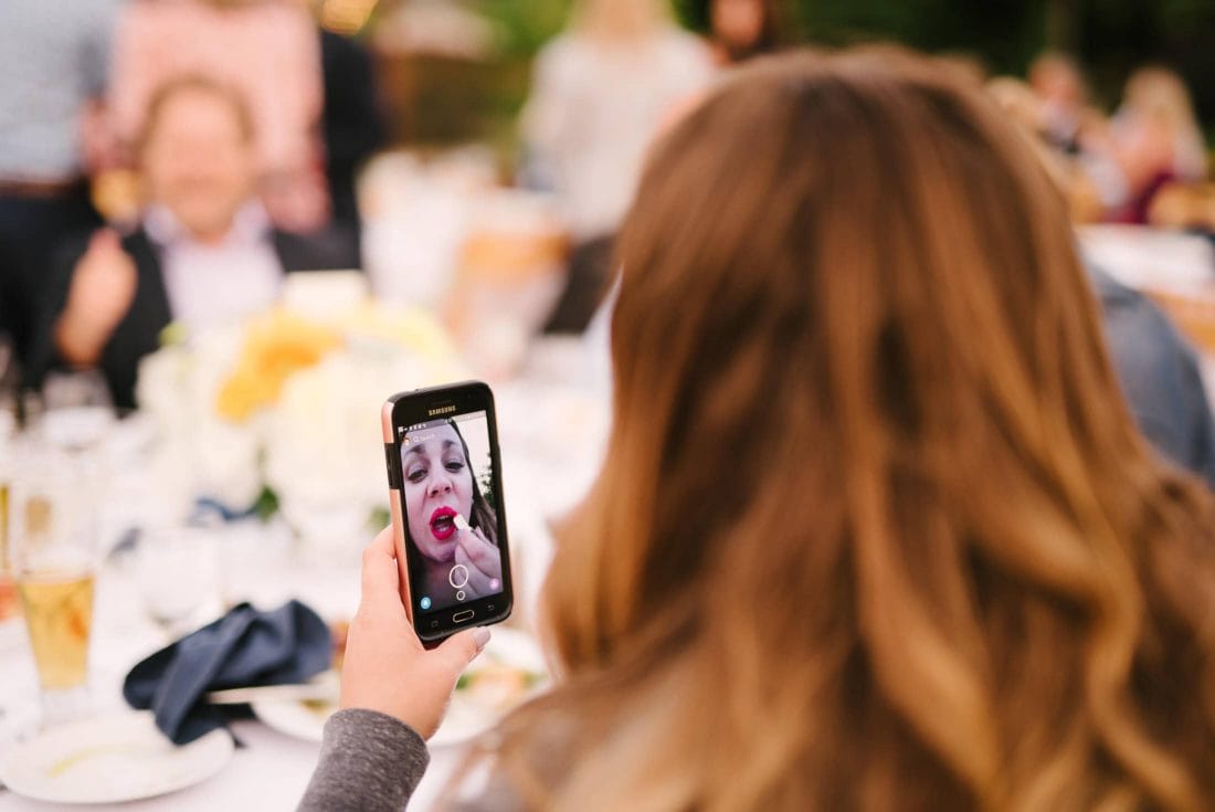 Great Pic of woman putting on lipstick at wedding
