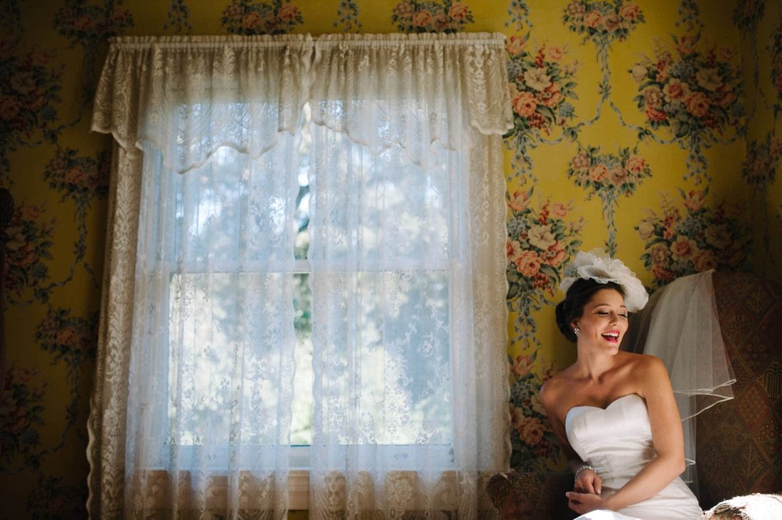 fun shot of bride against floral wall paper at Atherton Wedding